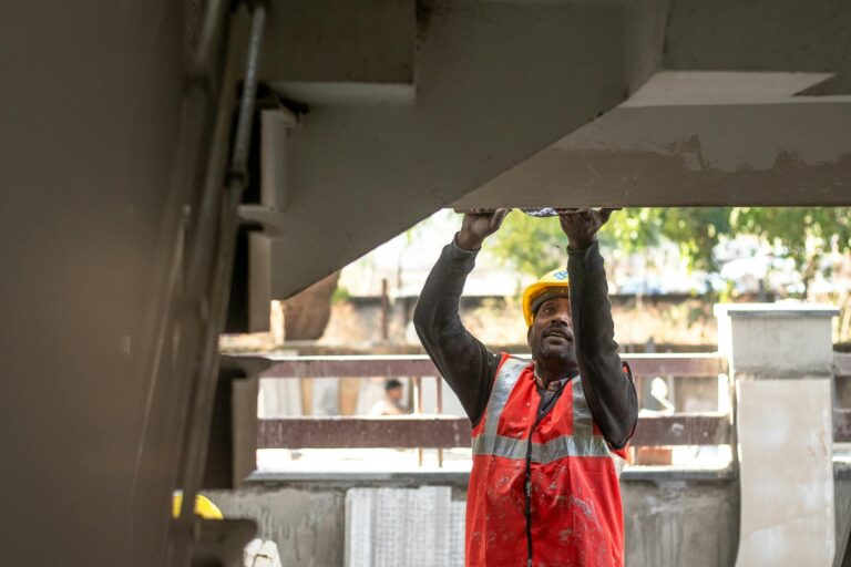 A construction worker inspects a building structure outdoors in Delhi, India.
